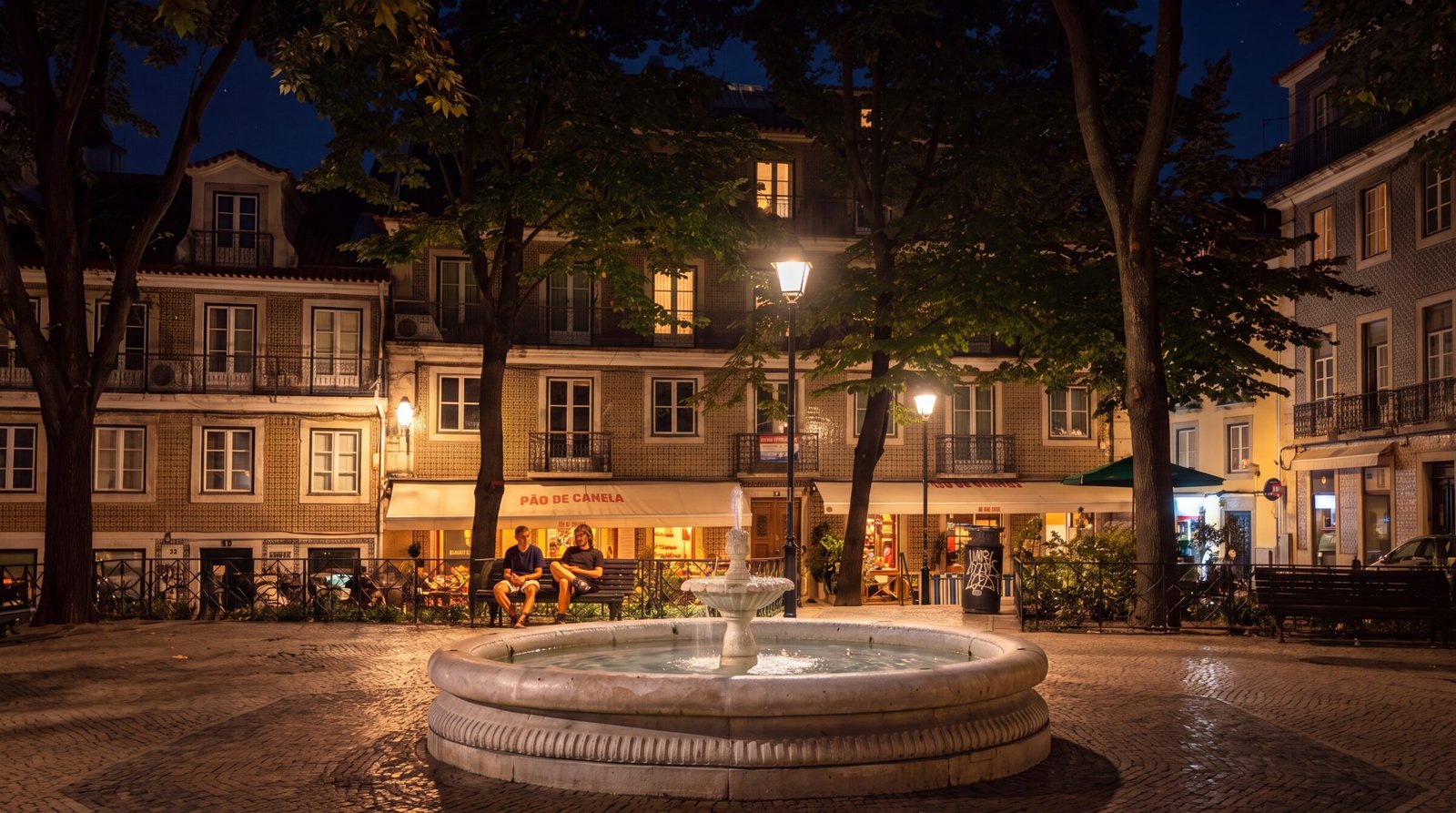 Praça das Flores at night: the fountain, lamplight and a lit café terrace